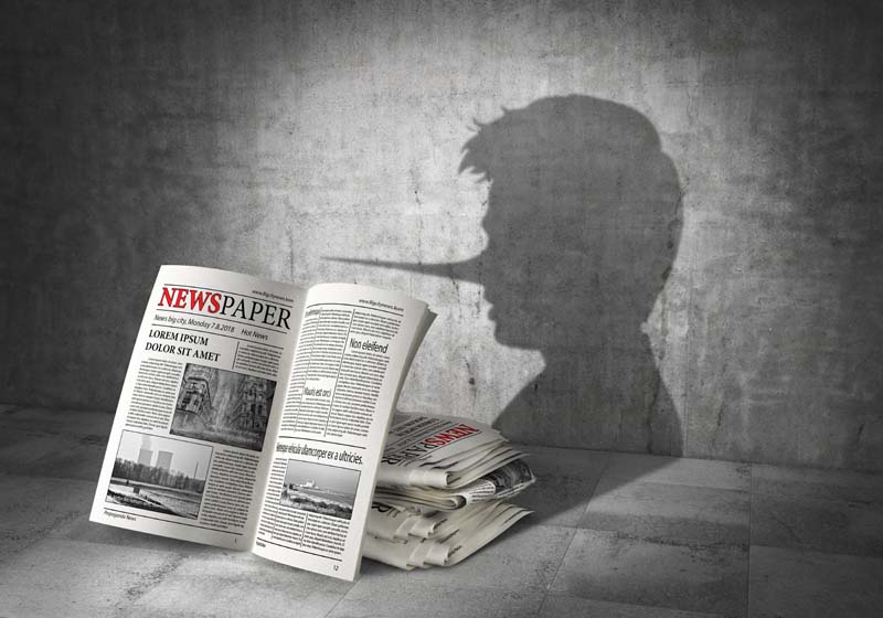 Newspaper image on a wall with a ong nosed man shadow.