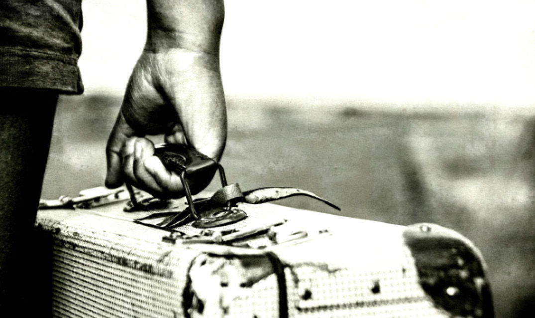 monochrome stock image of hand holding vintage suitcase
