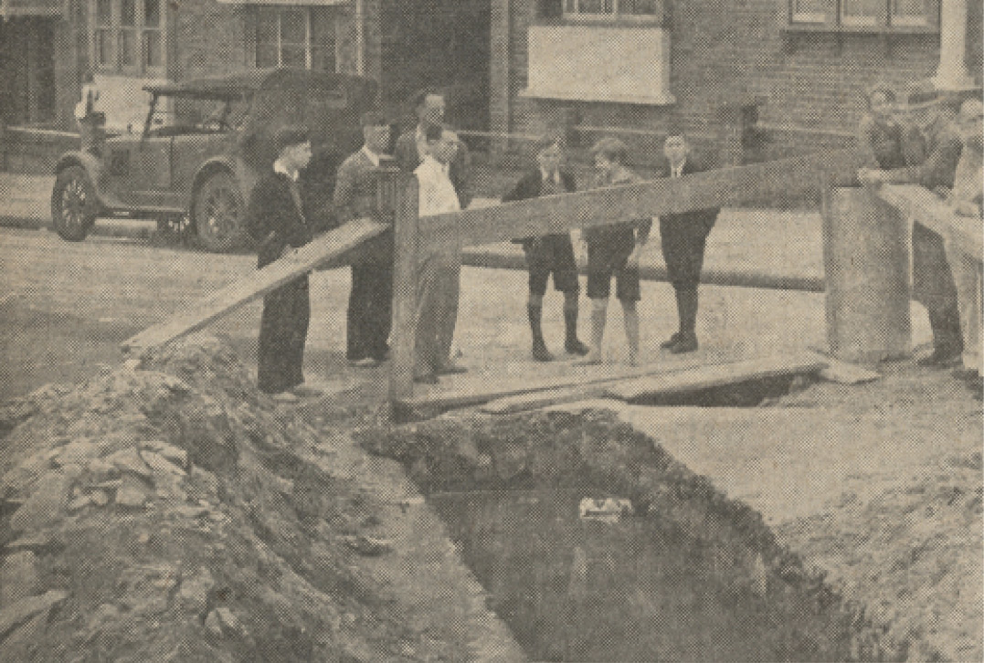 People standing and looking at the boarded up trench